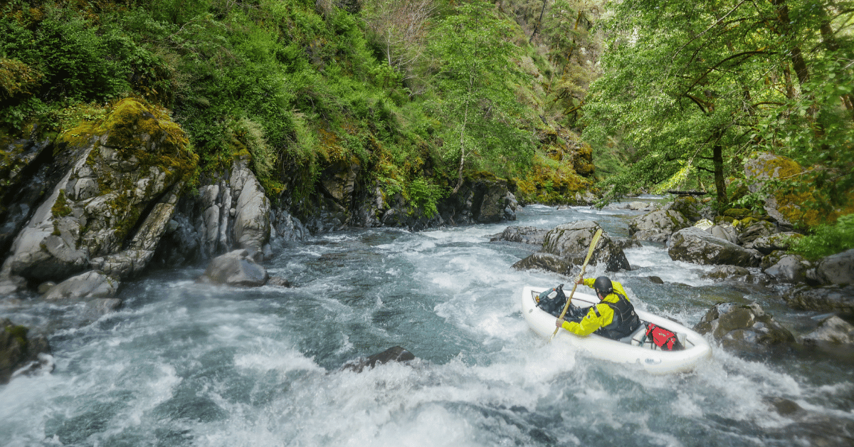 A kayaker paddles down the rushing water of Indigo Creek between steep rocks covered in vegetation by Priscilla Macy and Jacob Cruser 